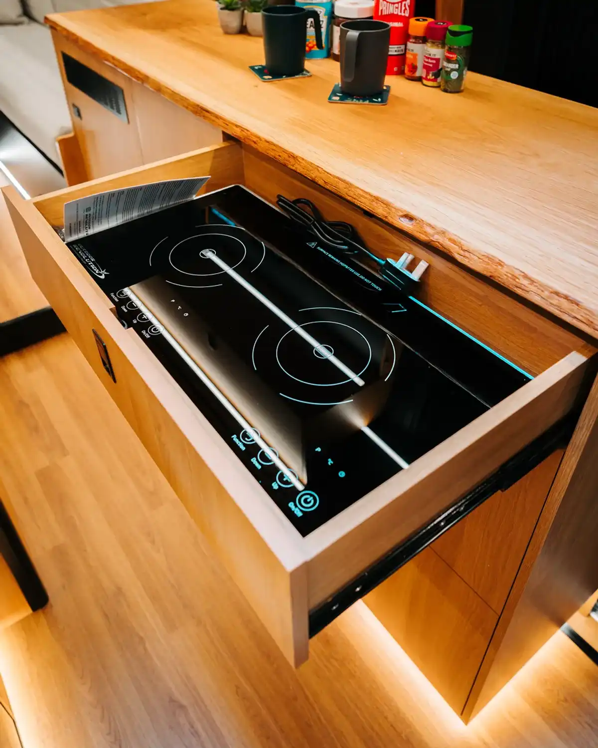 Two-ring induction hob pulled out of a drawer in the bespoke Mercedes Sprinter campervan