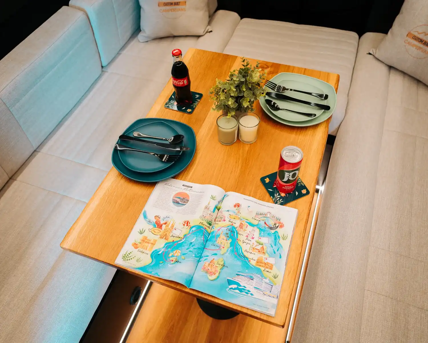 Lounge table laid with plates and a map in the bespoke Mercedes Sprinter campervan