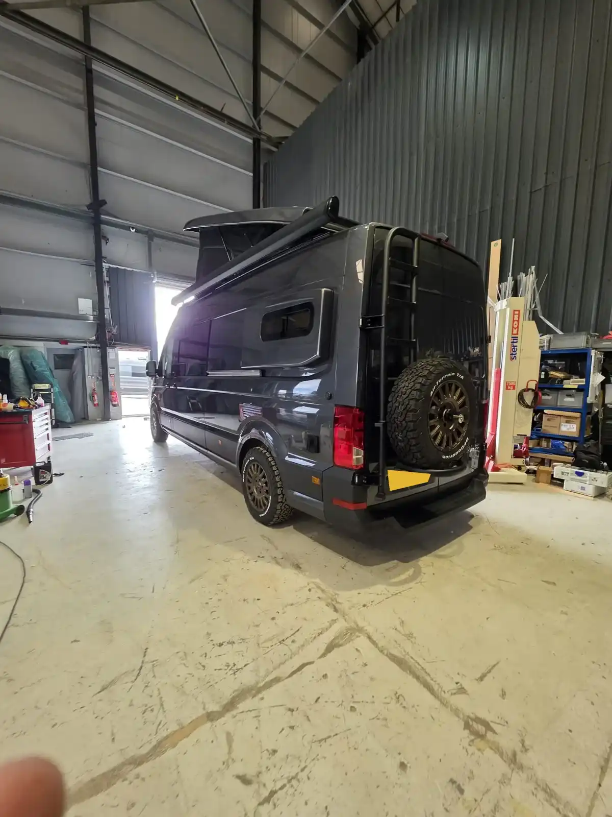 Back of a Luxus Pop-top MAN TGE campervan in the workshop, with the spare wheel carrier