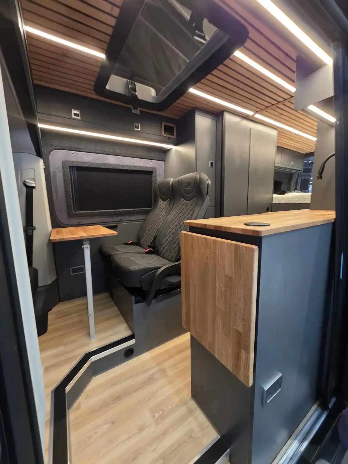 Seats, table and kitchen in a Luxus Pop-top MAN TGE campervan