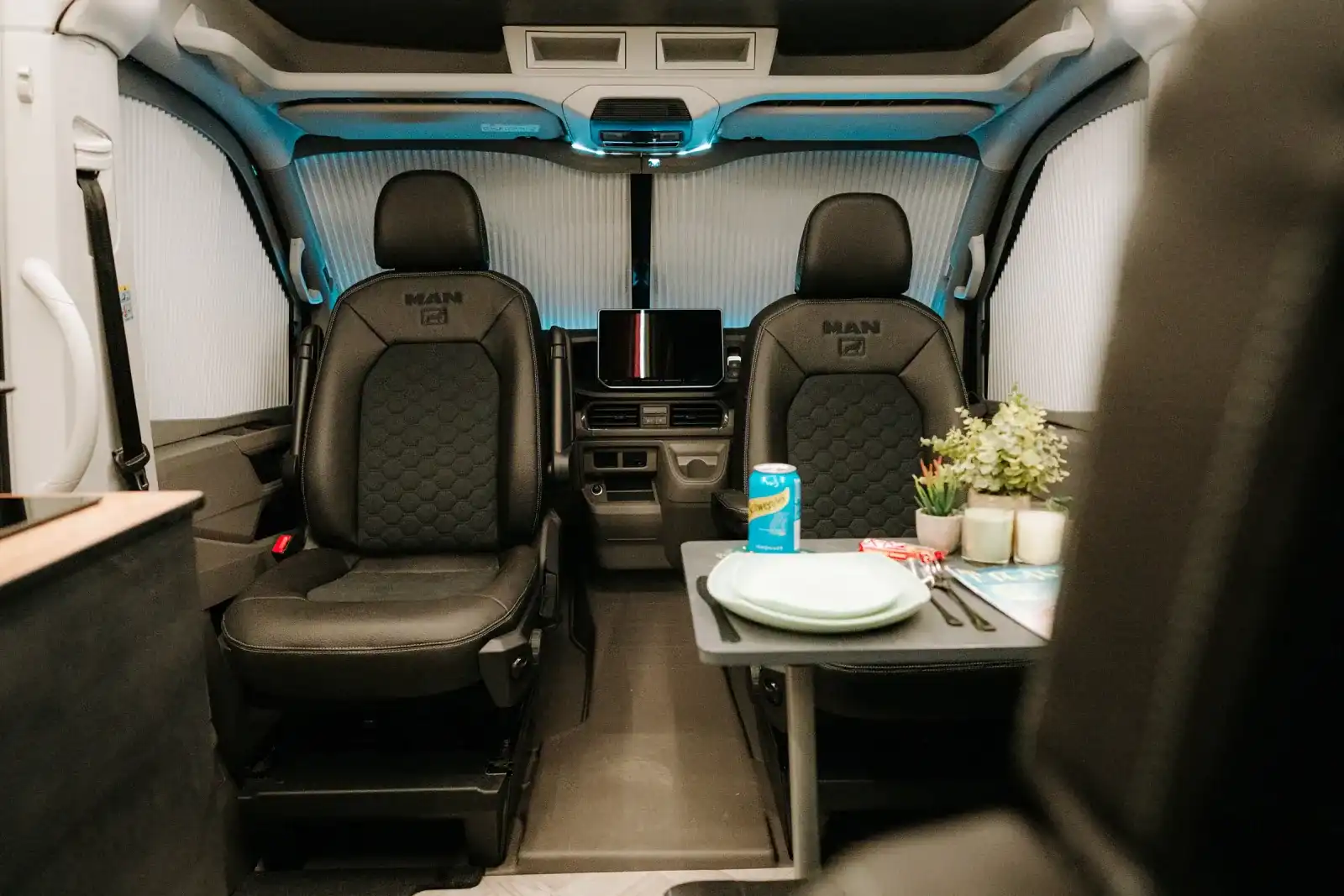 Swivel cab seats and the table set for lunch in a Ventus Pop-top campervan